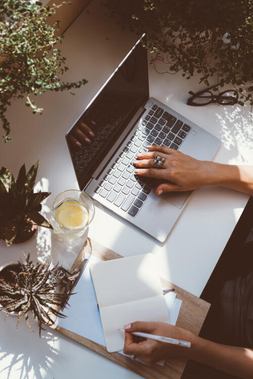 We see a woman's hands from above as she works at her desk.